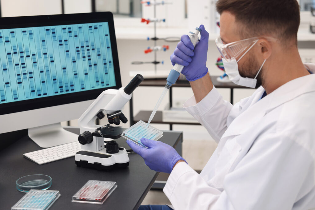 Research in genetics. Scientist with micropipette and microplate working at table in laboratory