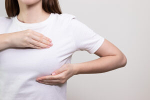 Woman performing breast self-exam, checking for any lumps or changes. Breast cancer awareness, breast check.