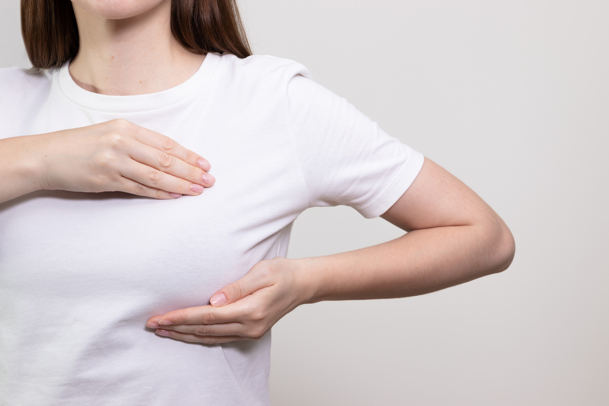 Woman performing breast self-exam, checking for any lumps or changes. Breast cancer awareness, breast check.
